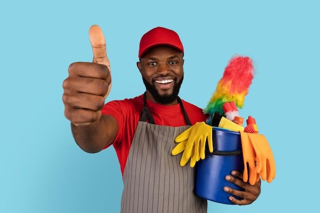 Professional cleaner with thumbs up and cleaning supplies